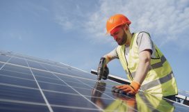 Alternative energy ecological concept. Male worker with solar batteries. Man in a protective helmet. Installing stand-alone solar panel system.