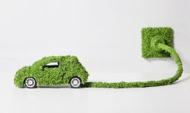 Electric car covered with grass connected to socket, close up Electric car covered with grass connected to socket, close up
